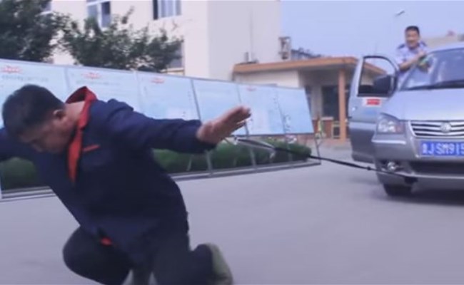 بالفيديو: صيني يسير بحذاء وزنه 300 كيلو جرام ويسحب سيارة برقبته!